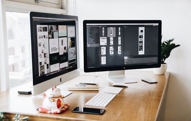 Two Mac computers with design elements displayed on screens