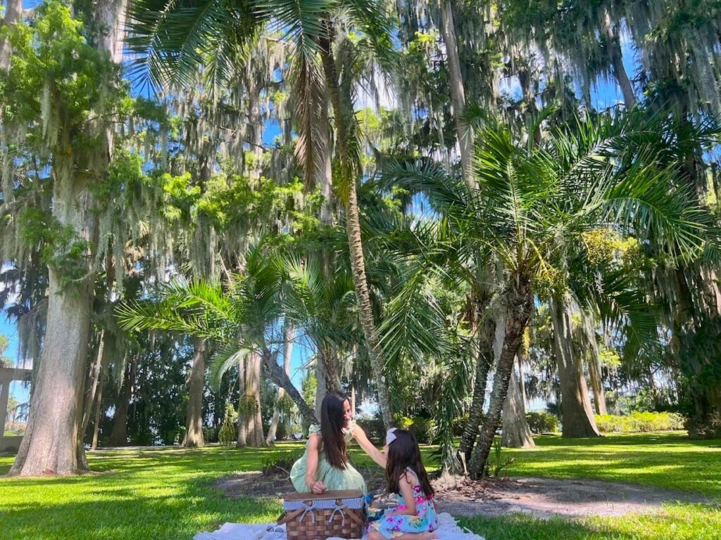 Melissa and her daughter sitting together on a blanket, with a picnic basket nearby