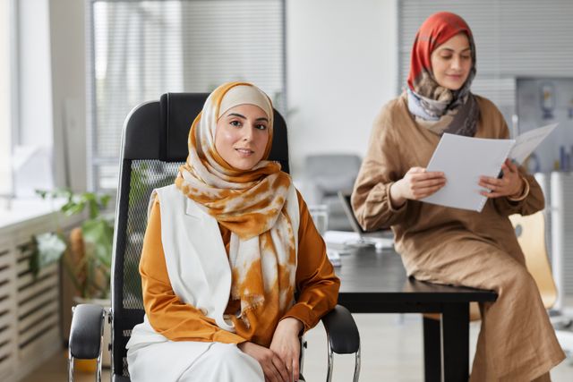 Two women with hijabs in a office setting