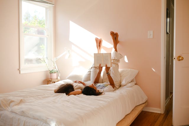 Mom and daughter reading a book with feet on wall 