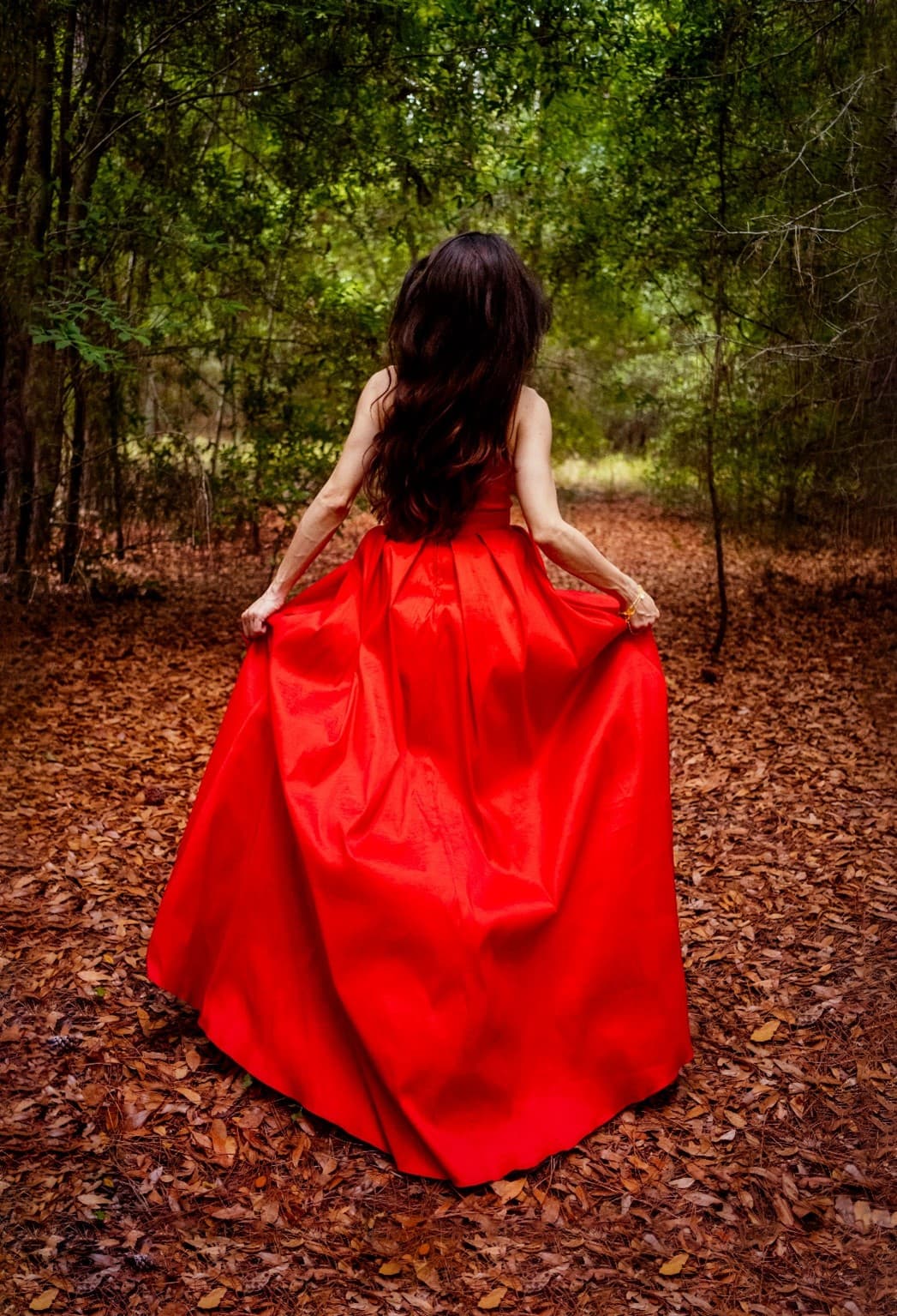 Melissa running in the woods in a red dress