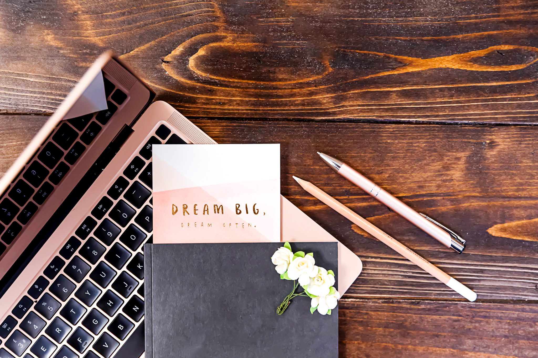 A table with a laptop, a notebook on top, and a Dream Big card inside the notebook