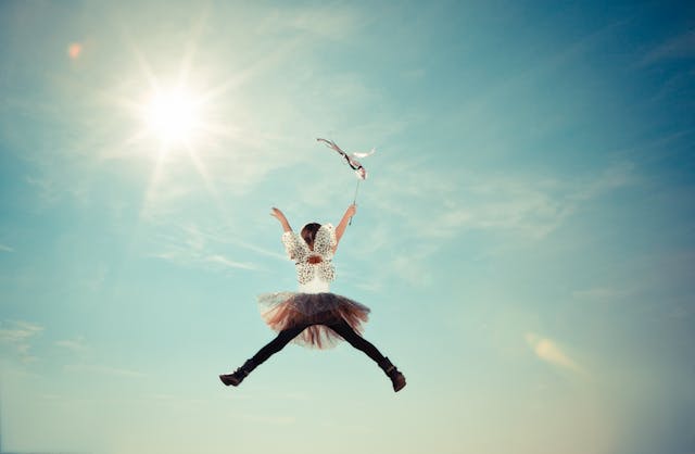 Child flying in the sky holding an umbrella