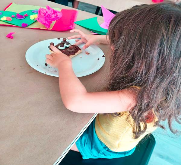 Melissa's daughter picking up a brownie she decorated