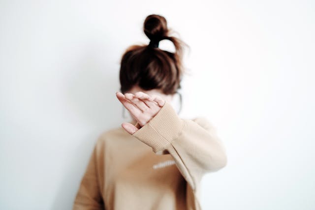 Standing woman covering her face with her hand