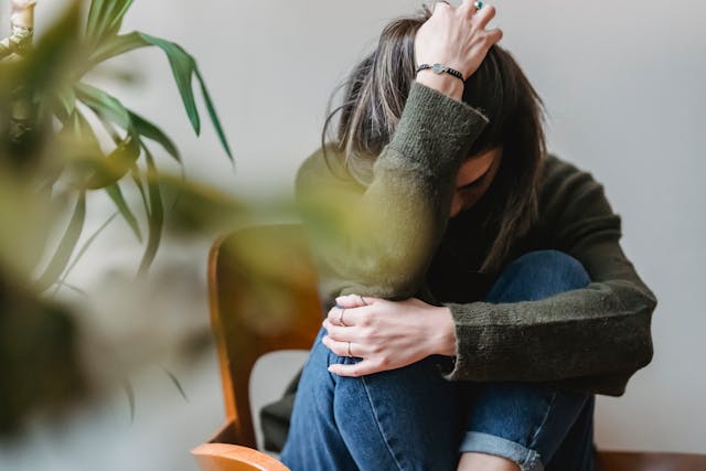 Seated woman with her legs crossed and her hand covering her face