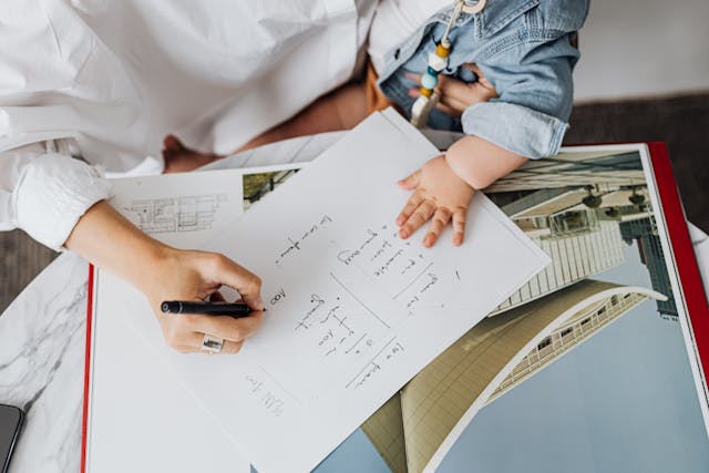 Mom writing on paper while holding her baby