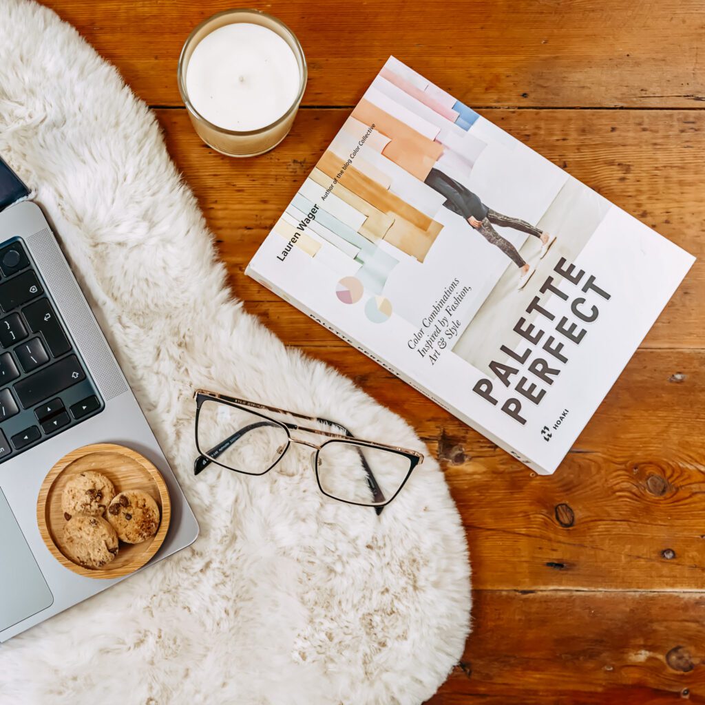 Color palette book near a laptop, eyeglasses, and a candle