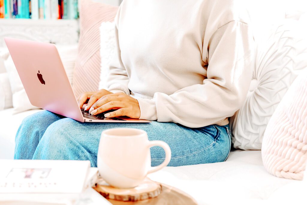Cropped view of a woman typing on her laptop while sitting on a sofa