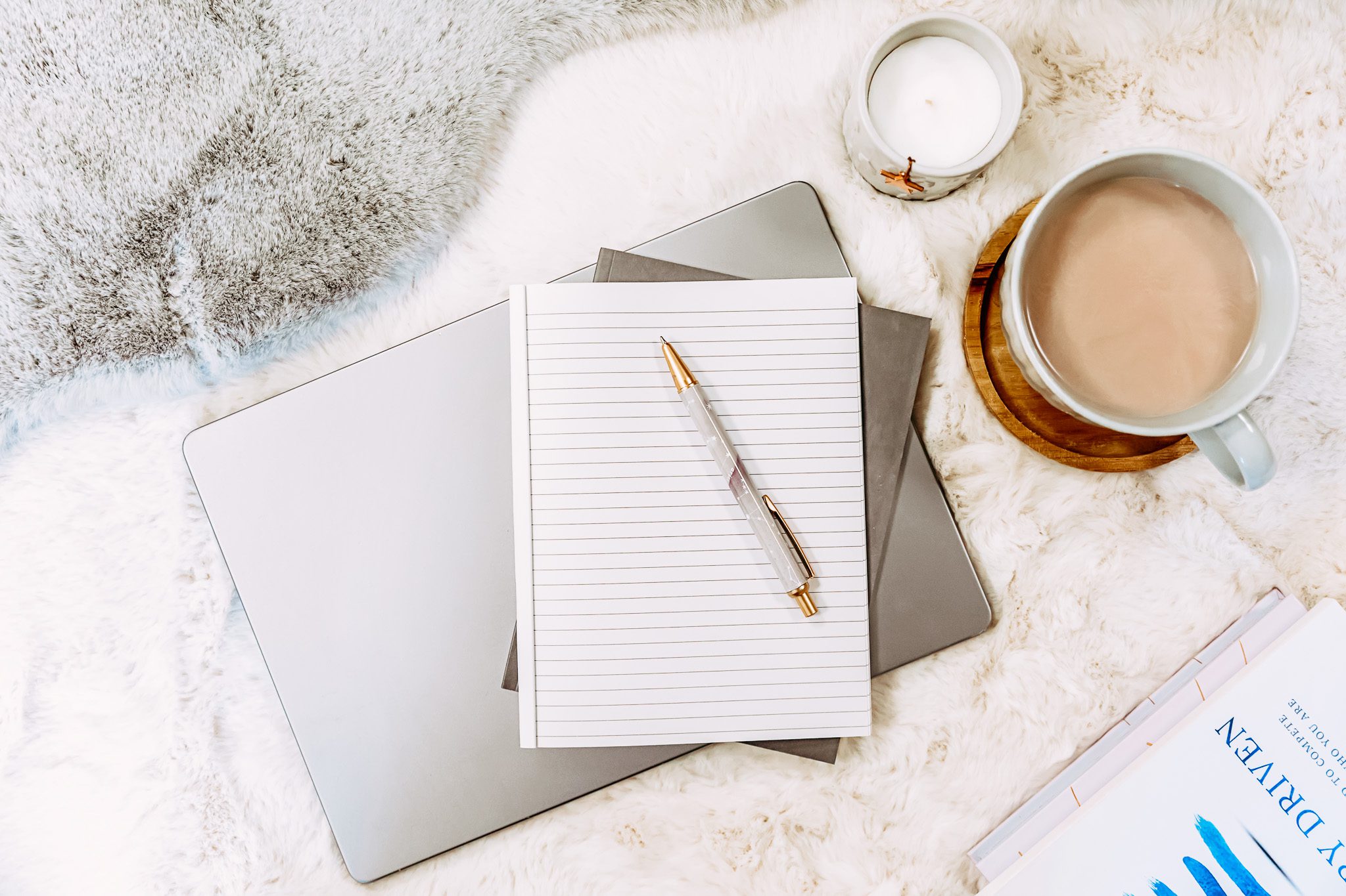 Notebook and pencil resting on a laptop beside a cup of coffee