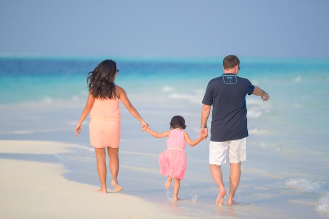 Family walking along the beach, wetting their feet in the sand