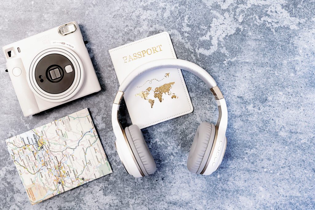Headphones on top of passport and near camera and folded map