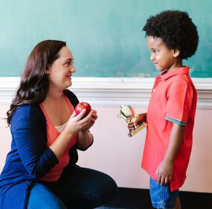 A teacher looking at her student while holding an apple
