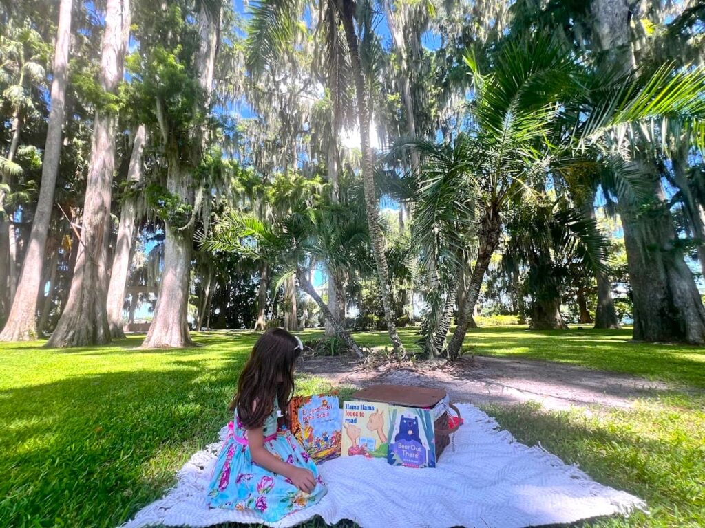 Melissa's daughter looking at books while sitting on picnic blanket