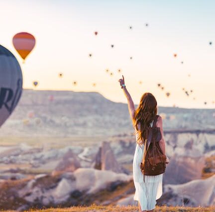 Woman pointing at hot air balloons in the sky