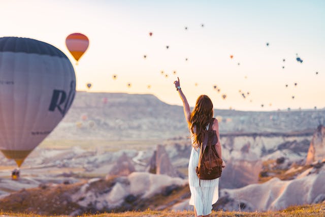 Woman pointing at hot air balloons in the sky