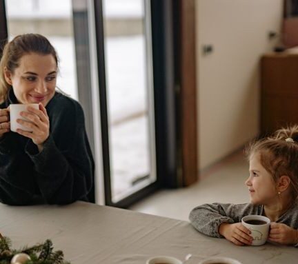 Mom and daughter smiling while drinking coffee