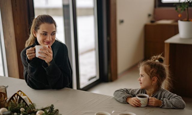Mom and daughter smiling while drinking coffee