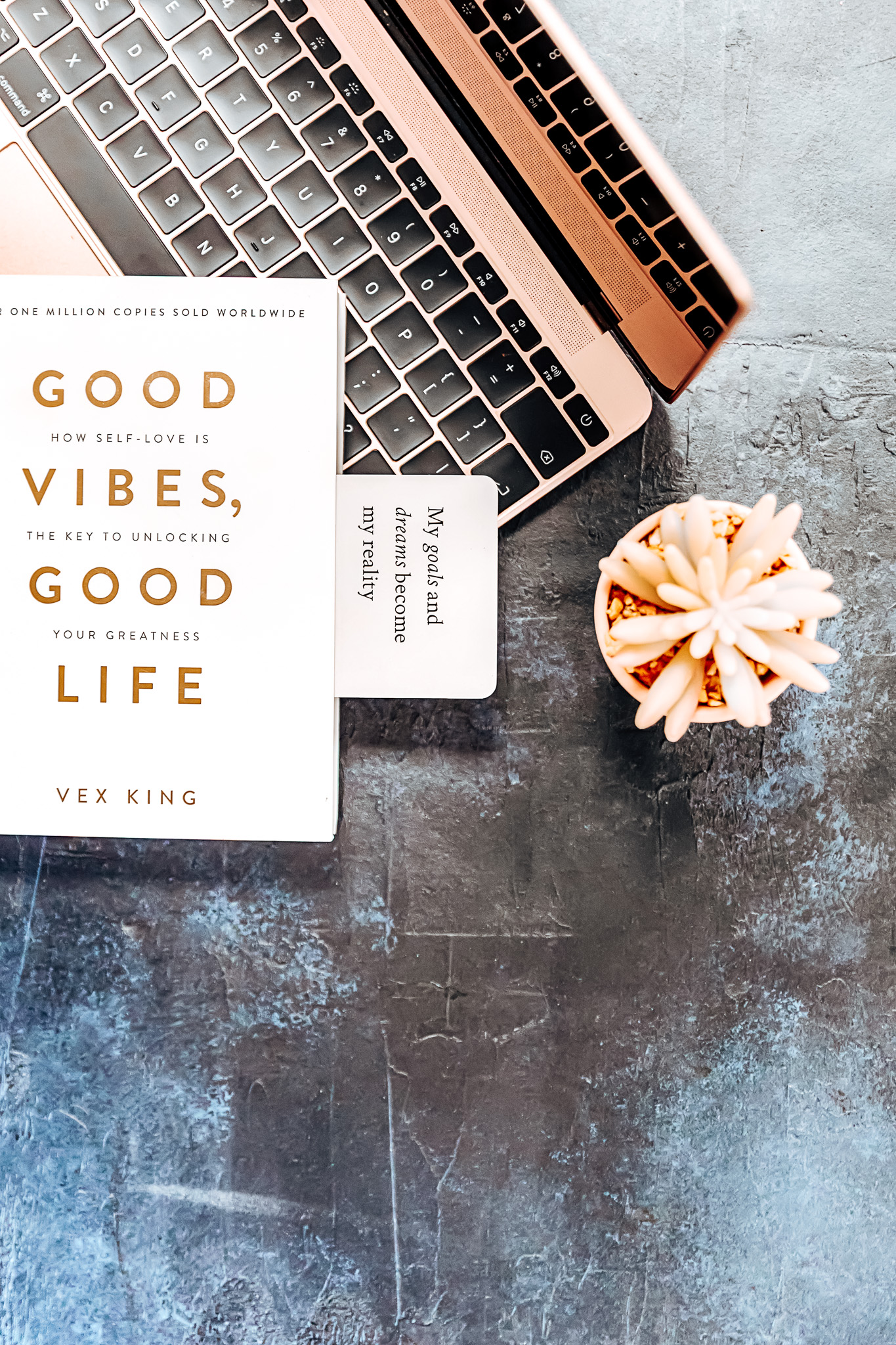 Motivational book with a positive quote inside, resting on a laptop