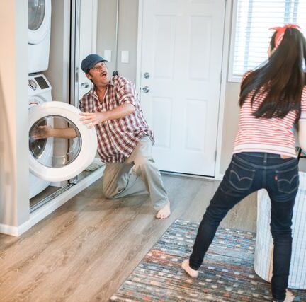 Father and daughter doing laundry together while laughing
