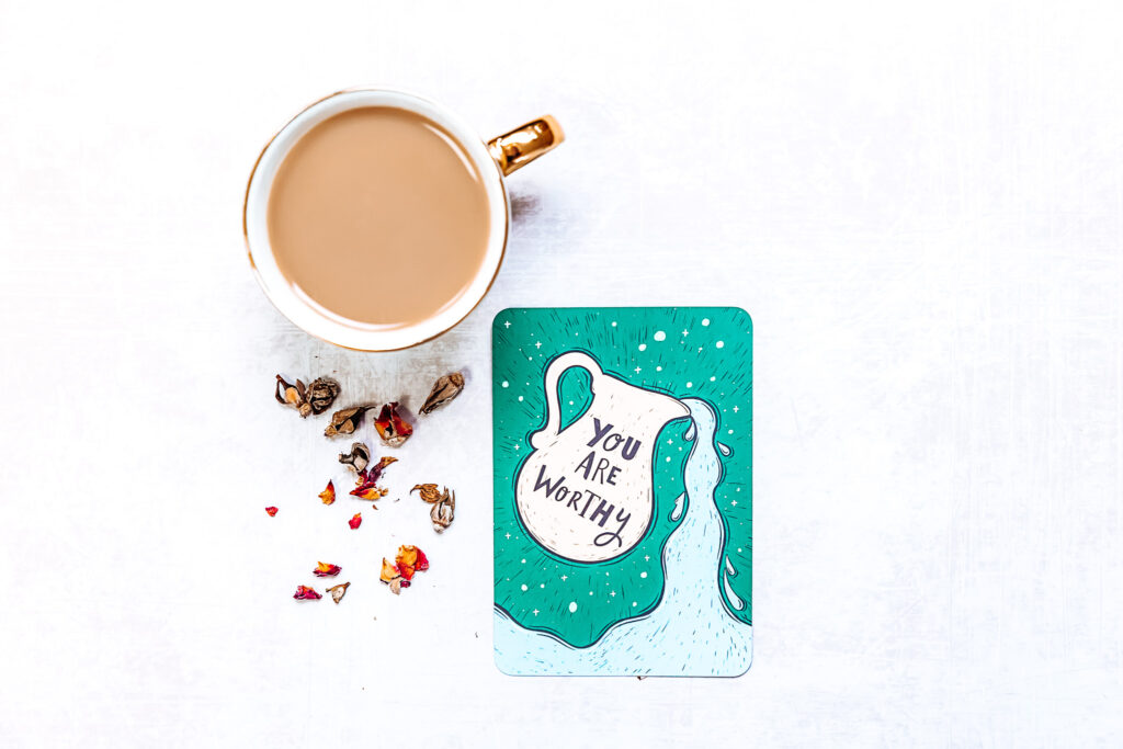 Printed motivational quote reading “You are worthy” placed next to a cup of coffee