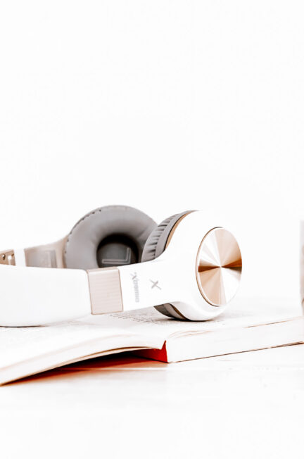 Headphones resting on a notebook beside a cup of coffee