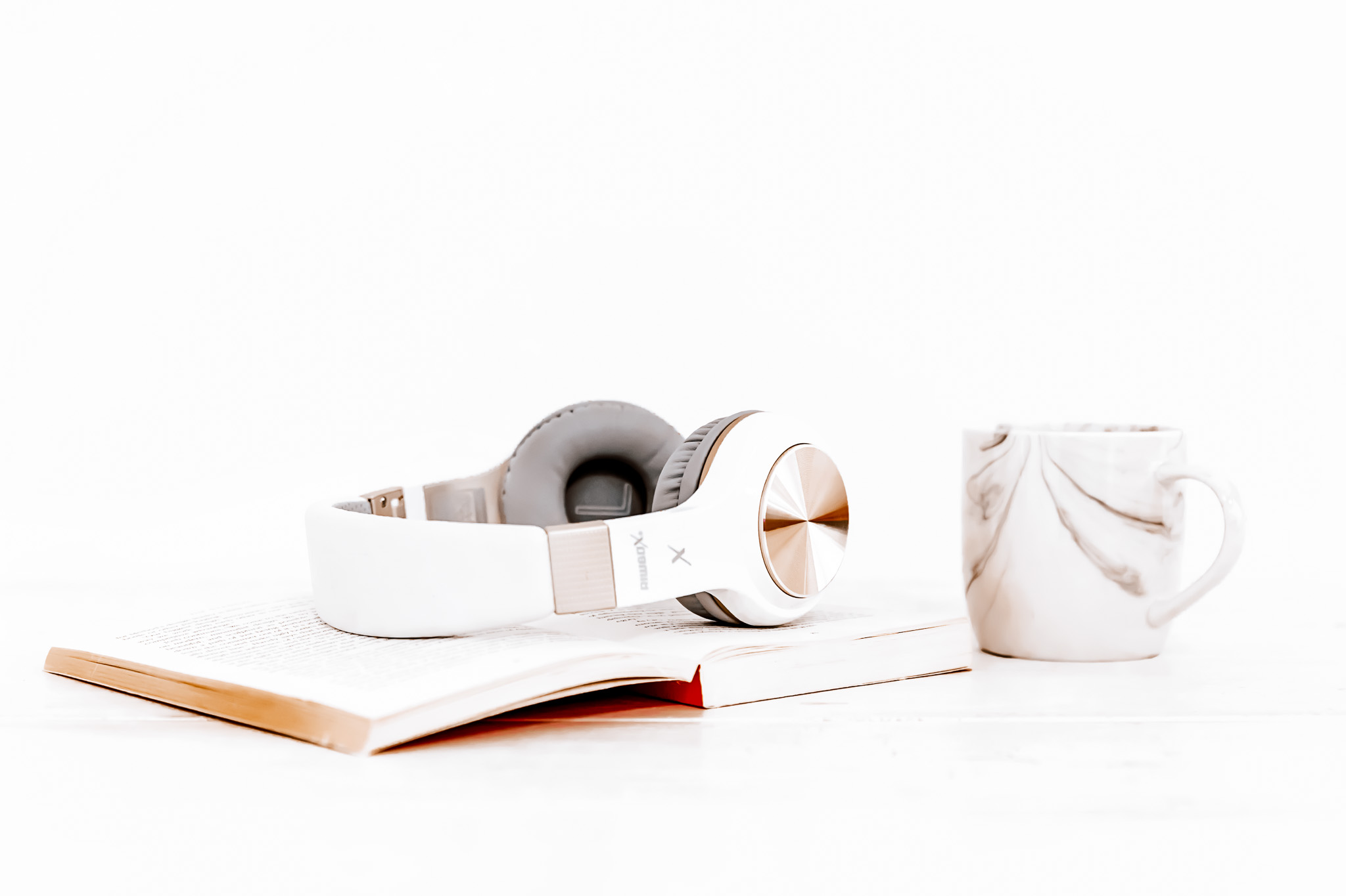 Headphones resting on a notebook beside a cup of coffee